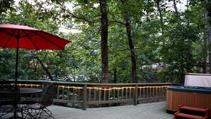 Eine Holzterrasse mit Whirlpool, Tisch und Stühlen sowie Lichterketten.