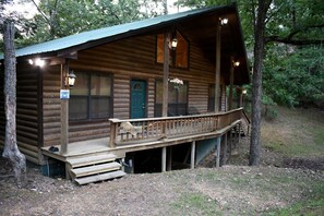 A log cabin with a porch, a green door, and a sign indicating a bent tree. - Fully Furnished Cabin with Fire Pit Perfect for Small Groups in Oklahoma (Broken Bow)