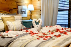 A hotel room with a bed adorned with rose petals and a towel shaped like a heart. - Fully Furnished Cabin with Fire Pit Perfect for Small Groups in Oklahoma (Broken Bow)