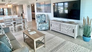 Un salon moderne comprenant un canapé, une table basse, un téléviseur et un ventilateur de plafond.