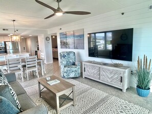 Ein modernes Wohnzimmer mit Sofa, Couchtisch, Fernseher und Deckenventilator.