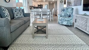 Un salon avec un canapé gris, des coussins à motifs, une table basse et un tapis à motifs.