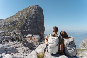 A couple with backpacks sitting on a rocky outcrop overlooking a mountain village.