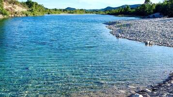 A river with clear water, surrounded by rocky terrain and greenery.
