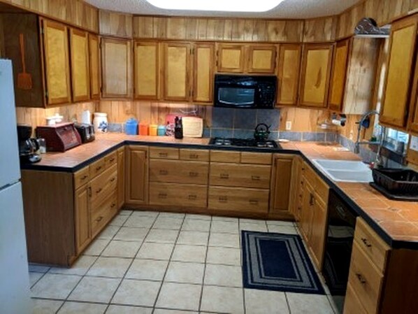 A kitchen with wooden cabinets, a microwave, a stove, and a sink.