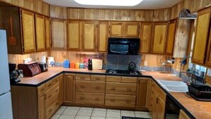 Une cuisine avec des meubles en bois, un four à micro-ondes, une cuisinière et un évier.