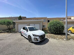 Een witte auto geparkeerd op een oprit, met een garage op de achtergrond.