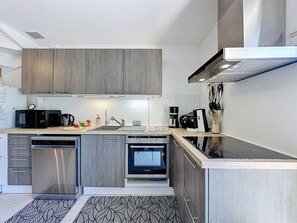 A modern kitchen with grey cabinets, stainless steel appliances, and a black and white patterned rug. - Mas des Vignes - La Pimprenelle by Interhome (Calvisson)