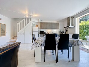 A modern kitchen with a dining area, a staircase, and a view of greenery. - Mas des Vignes - La Pimprenelle by Interhome (Calvisson)