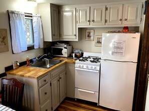 Cocina compacta con fregadero, estufa, microondas y refrigerador.