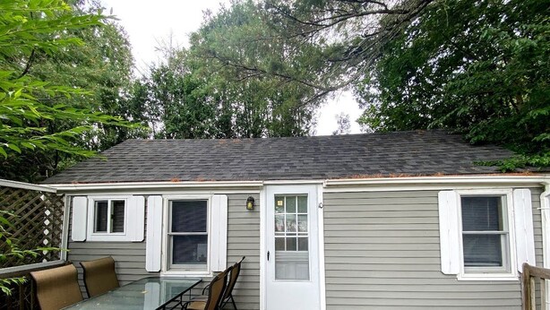 Une petite maison avec un patio, une table et des chaises, et une porte.