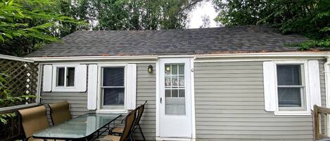 A small house with a patio, a table with chairs, and a door.