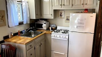 Cocina compacta con fregadero, estufa, microondas y refrigerador.