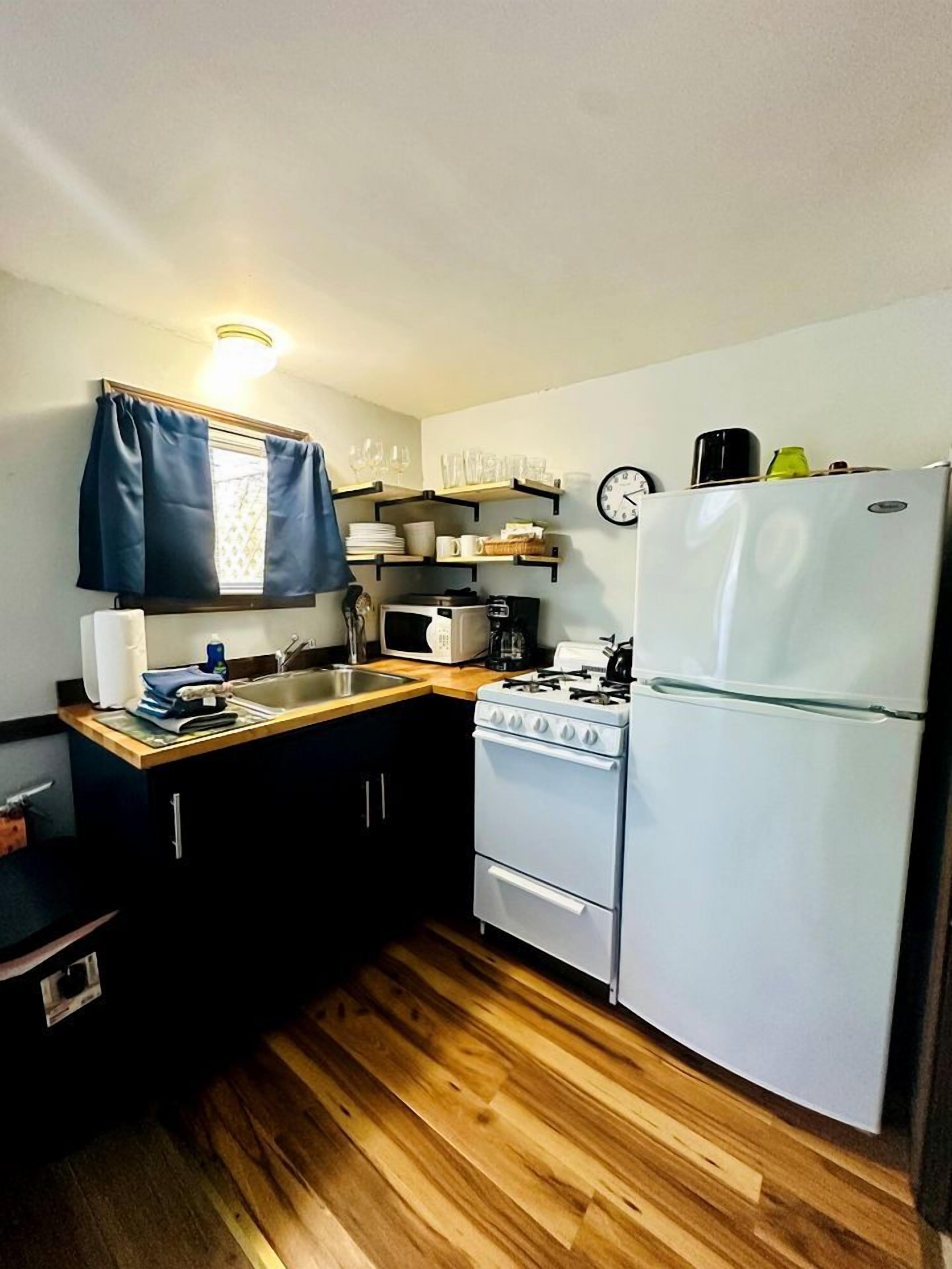 Une cuisine de taille réduite, équipée d’une cuisinière, d’un évier et d’un réfrigérateur.
