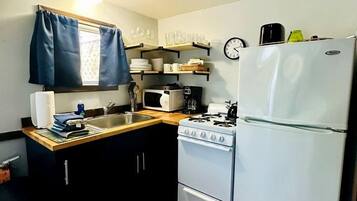 Une cuisine de taille réduite, équipée d’une cuisinière, d’un évier et d’un réfrigérateur.