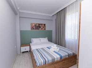 A bedroom with a bed, a nightstand, a painting, and a window with curtains. - SİNORA APART (MERKEZ)