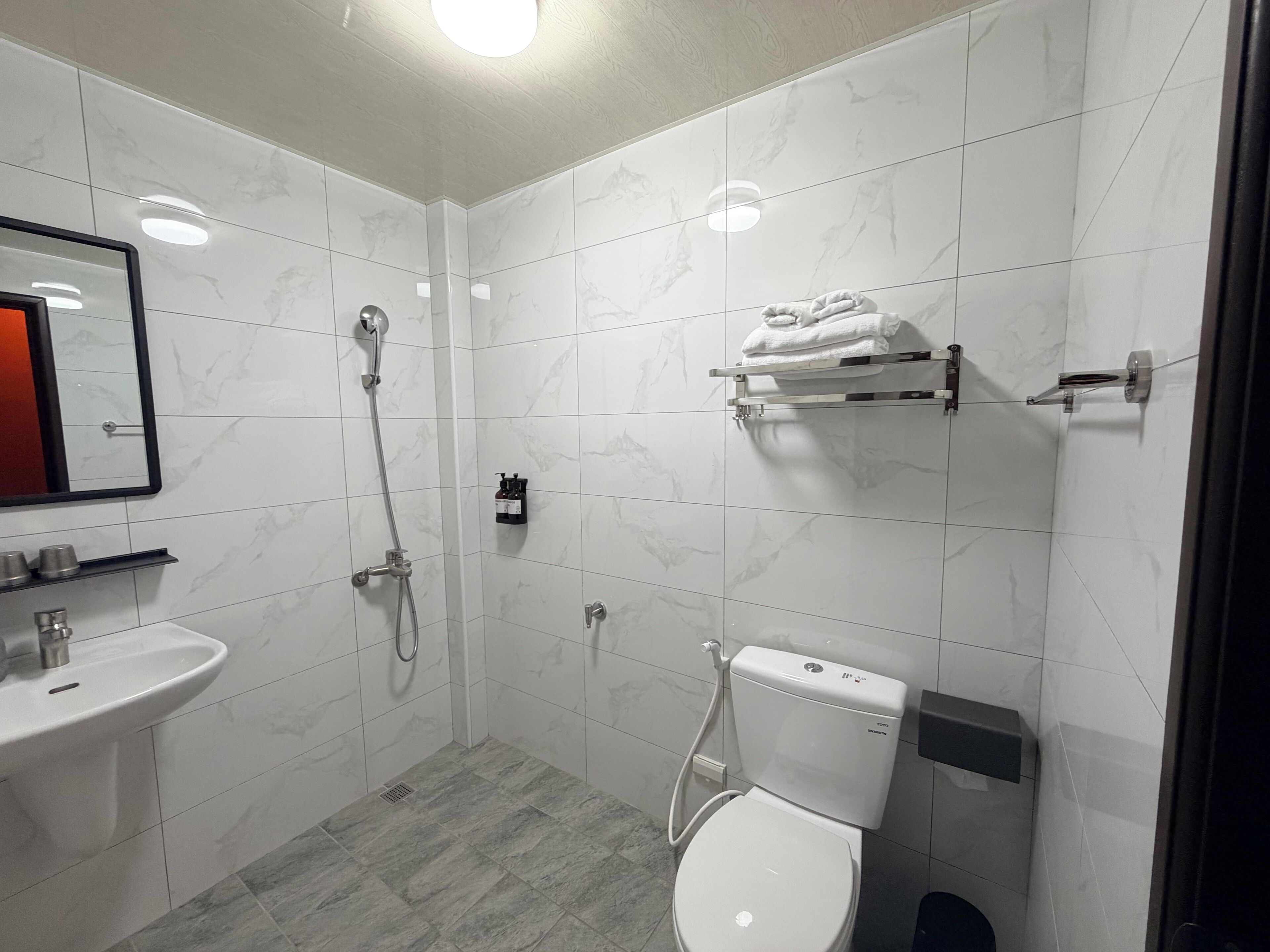 Un baño moderno con lavamanos, inodoro, ducha y toallero.
