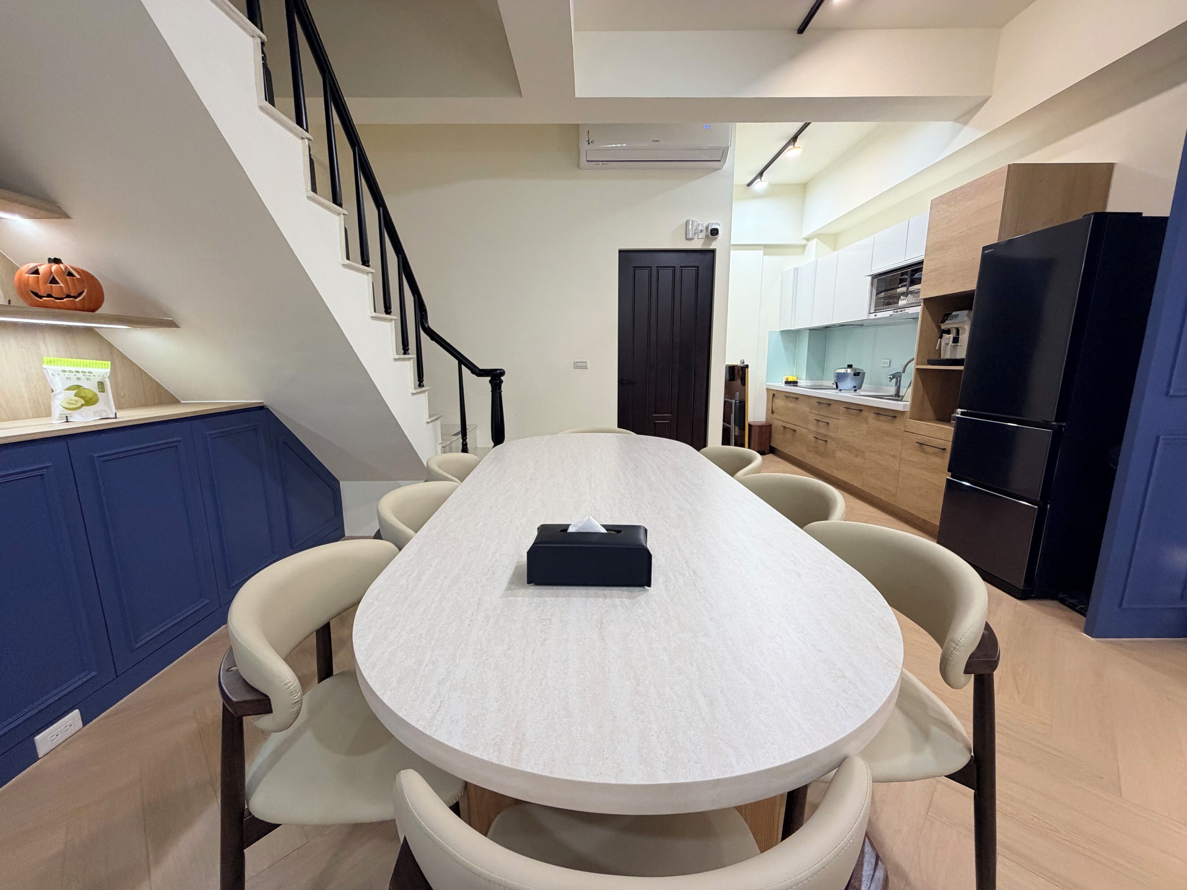 A modern kitchen with a dining area, a staircase, and a door.