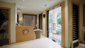 A reception area with a reception desk, a clock, and a staircase leading to an upper floor.