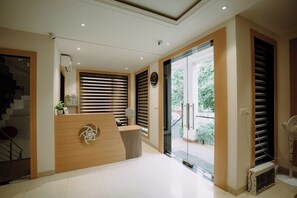 A reception area with a reception desk, a clock, and a staircase leading to an upper floor.