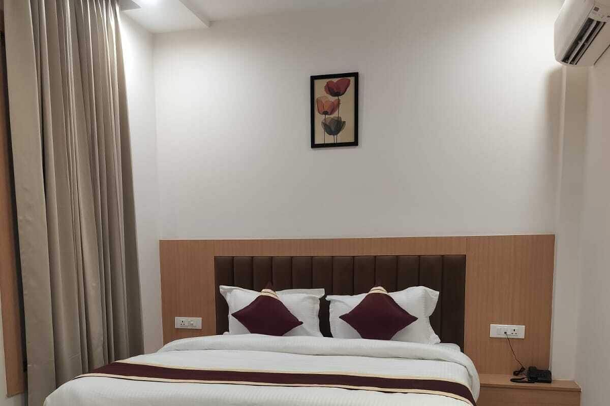 Ein Hotelzimmer mit einem Bett, einem Nachttisch, einer Klimaanlage und einem Bild an der Wand.