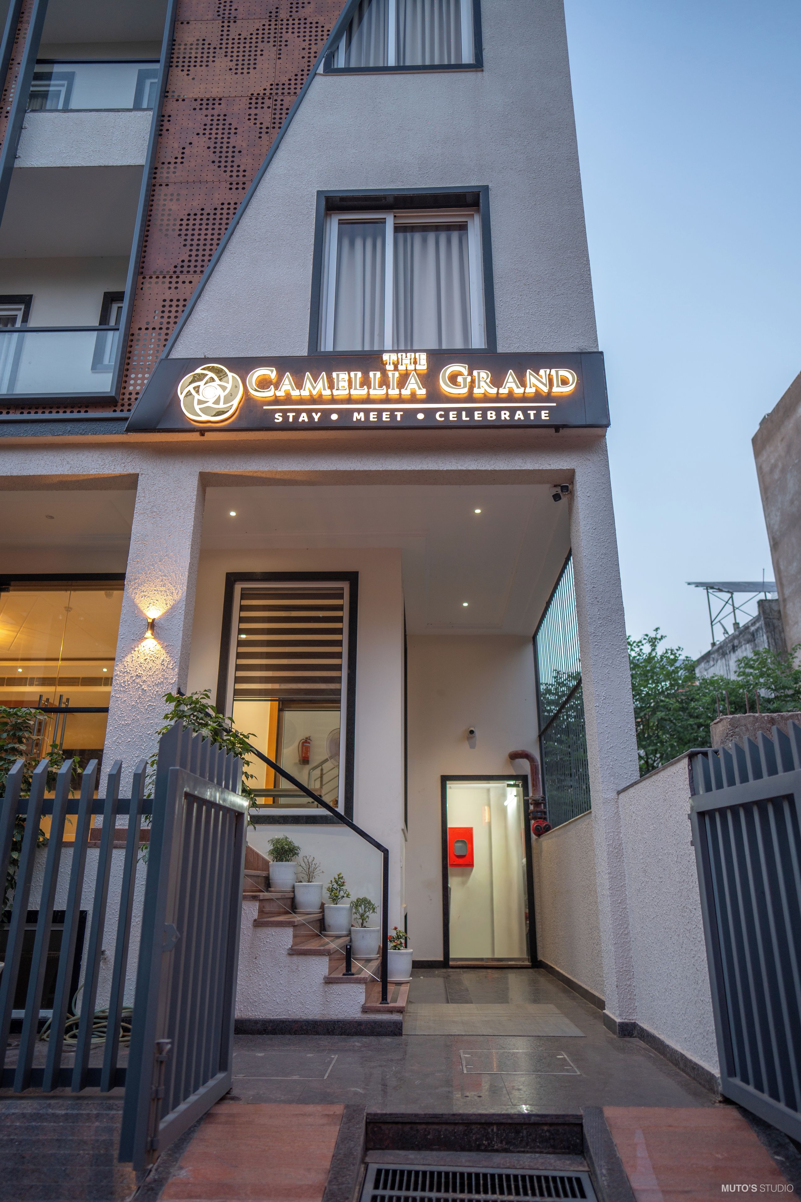 En hotelindgang med et skilt, der siger 'The Camellia Grand Stay Meet Celebrate'.