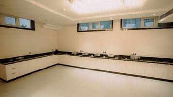 A spacious kitchen with white cabinetry, a black countertop, and a large chandelier.
