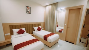 A hotel room with two beds, a mirror, a wardrobe, and a painting on the wall. - The Camellia Grand  (Lucknow)