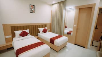 A hotel room with two beds, a mirror, a wardrobe, and a painting on the wall.