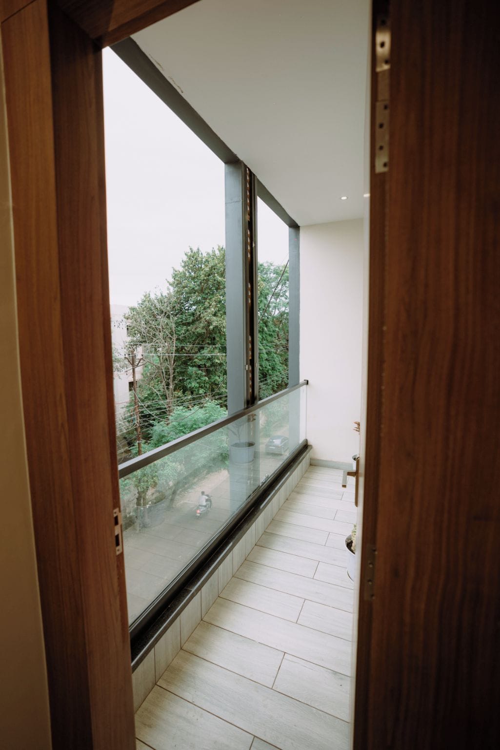 Ein Korridor mit einem Glasbalkon, einem Holzrahmen für die Tür und Fliesenböden.