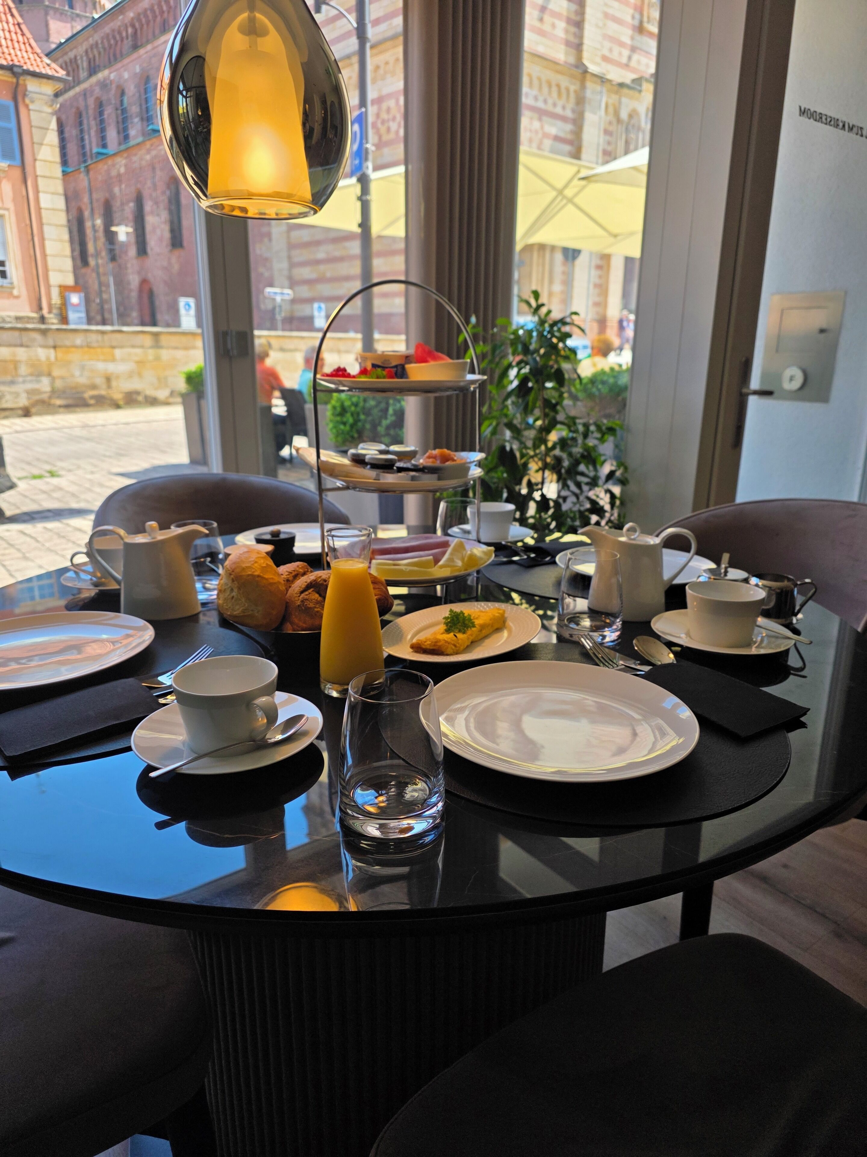 Una mesa de desayuno con platos, tazas y una bandeja escalonada de comida.