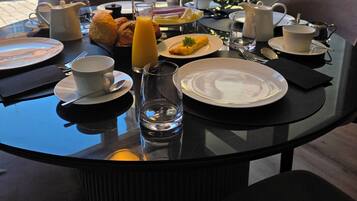 Una mesa de desayuno con platos, tazas y una bandeja escalonada de comida.