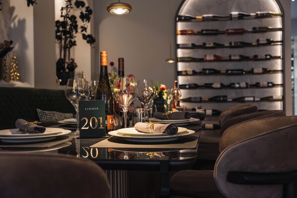 Un restaurante con una bodega, mesas dispuestas con platos, copas y botellas.