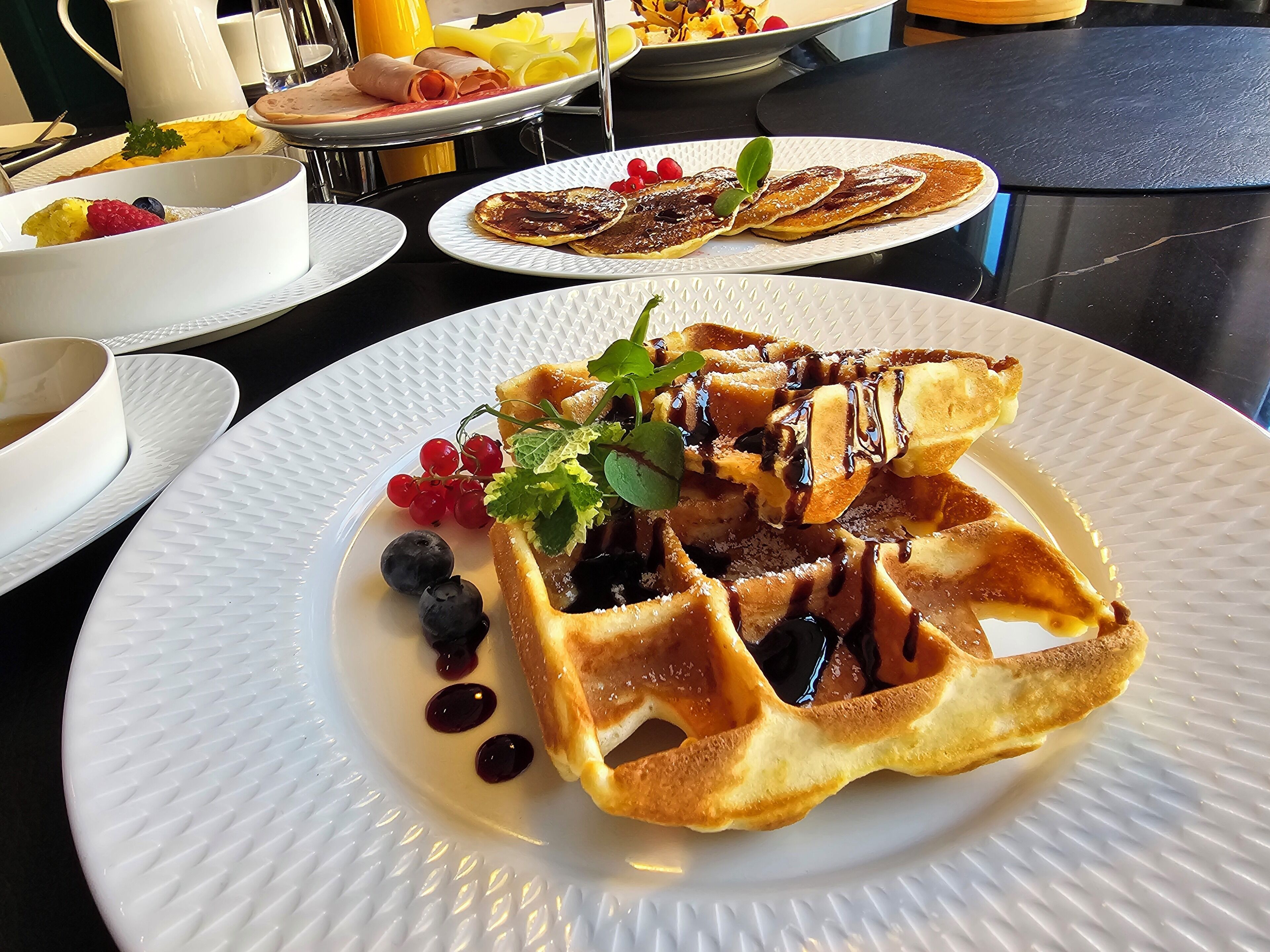 A breakfast setting with waffles, berries, and syrup on plates.