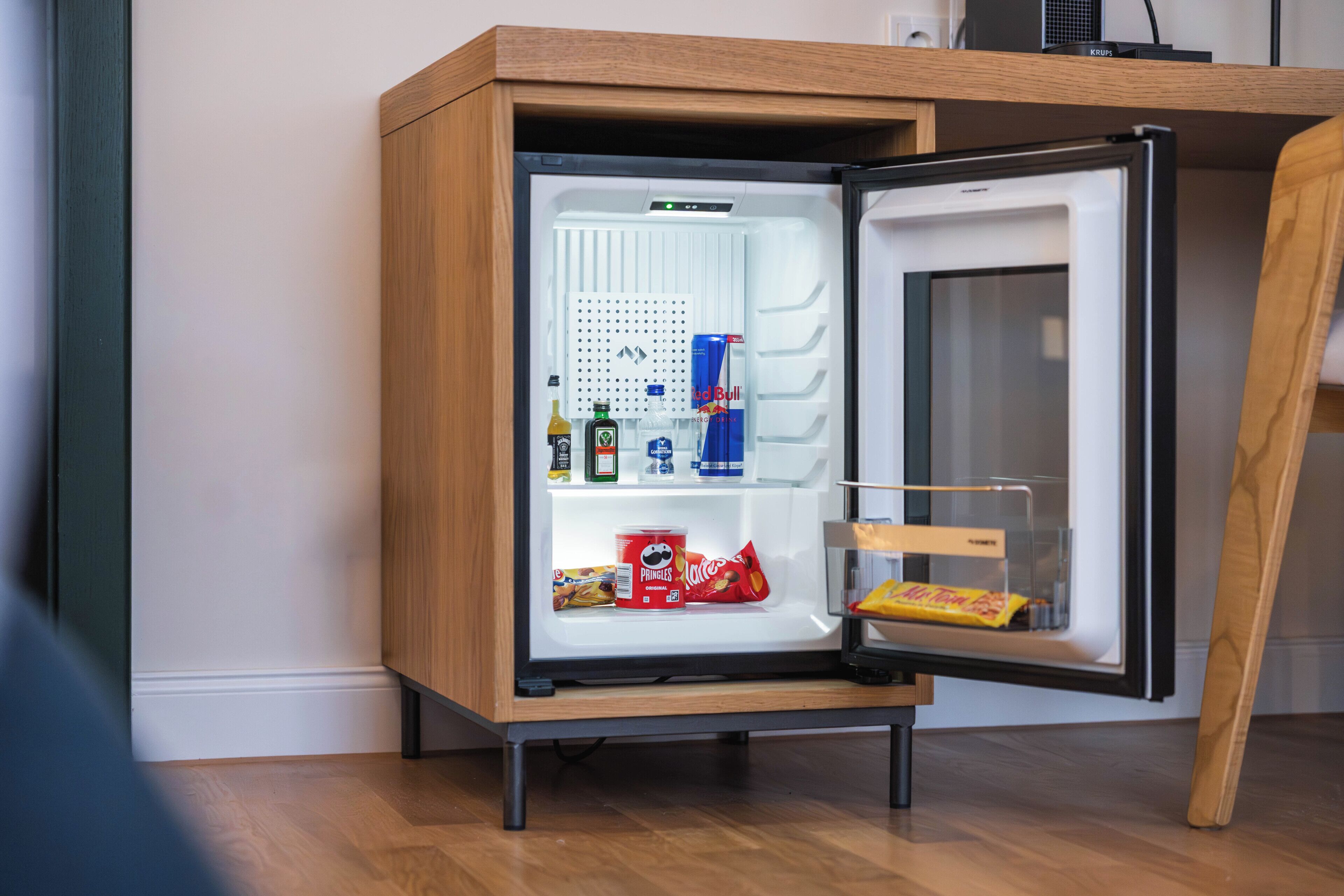A compact refrigerator with a wooden exterior, a small freezer compartment, and a glass door.