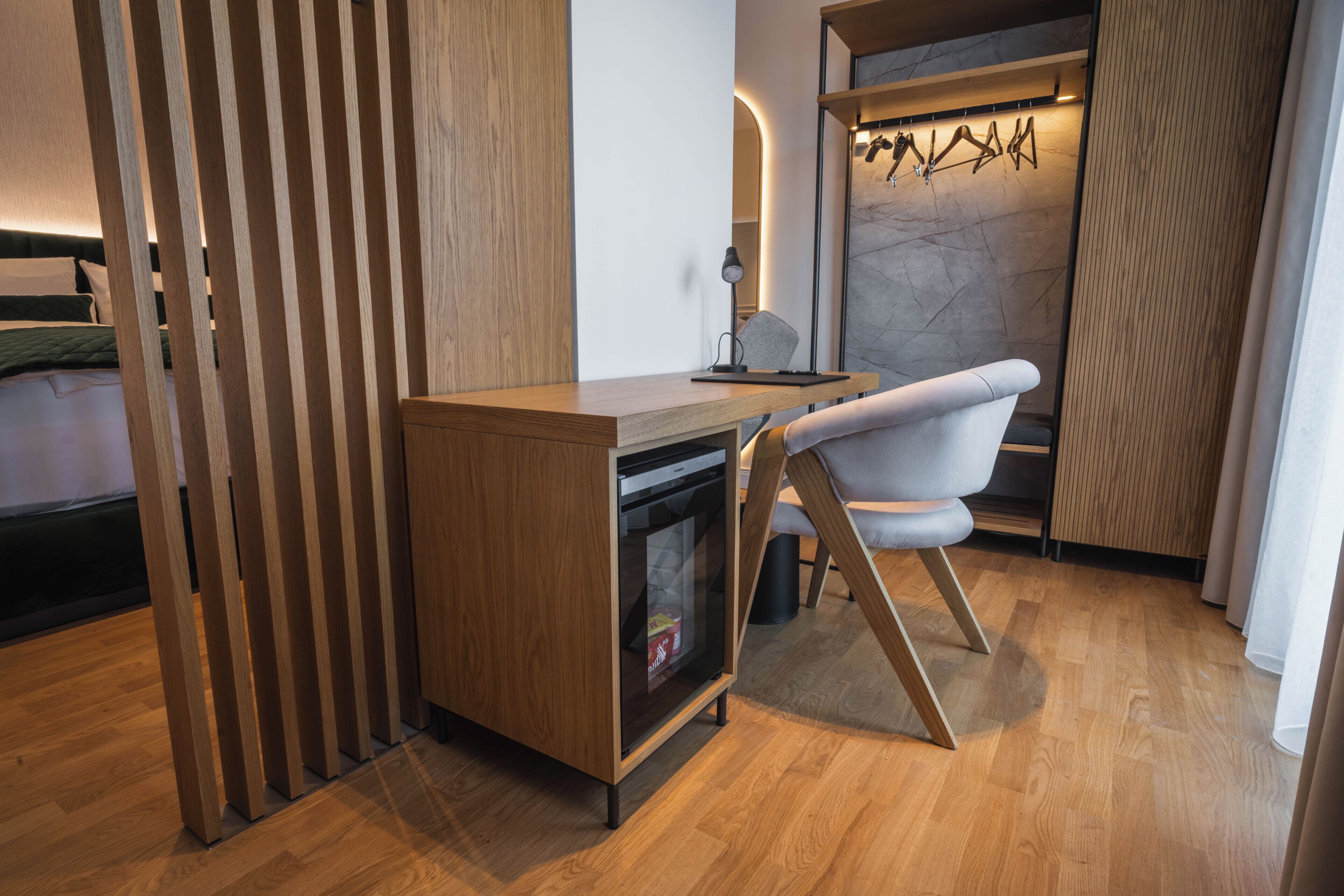 A modern room with a wooden desk, a chair, a built-in oven, and a marble wall.