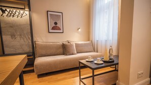 Uma sala de estar moderna com um sofá, uma mesa de centro e uma obra de arte emoldurada na parede.