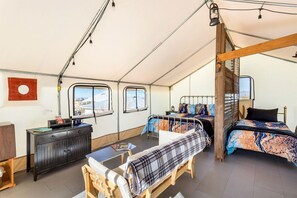 Een tentaccomodatie met een stapelbed, een bureau en een eettafel.