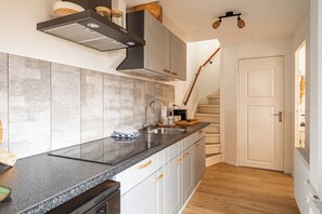 Eine moderne Küche mit Granit Arbeitsplatte, Edelstahlspüle und eingebautem Herd.