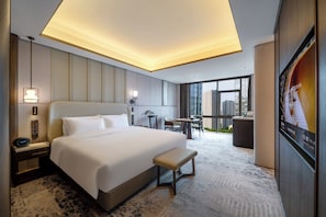Habitación de hotel con una cama grande, mesitas de noche, un escritorio y vistas a la ciudad.