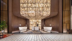 A modern bathroom with two marble sinks, a central mirror, and a patterned floor. - International Hotel LuoYang (Luoyang)