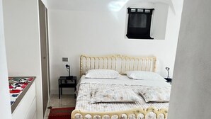A bedroom with a bed, a nightstand, a small window, and a red carpet. - 'Crooked House' Apartment with Mountain View, Private Garden and Parking (Naggio)