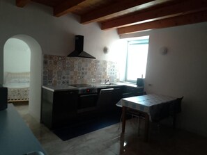 Una cocina con salpicadero de piedra, una ventana y una zona de comedor con mesa y sillas.