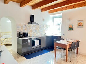 Une cuisine compacte dotée d’une cuisinière moderne, d’une machine à café et d’un dosseret carrelé.