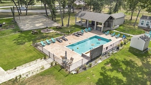 An aerial view of a backyard with a swimming pool, lounge chairs, a barbecue area, and a covered patio. - Relaxing Tiny Home Retreat with Pool, Goats & Firepits near Houston in Hempstead, Texas (Hempstead)