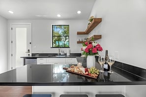 A modern kitchen with a central island, a window with a view, and built-in shelves. - Relaxing Tiny Home Retreat with Pool, Goats & Firepits near Houston in Hempstead, Texas (Hempstead)