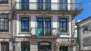 A multi-story building with balconies, a green door, and a flower display.