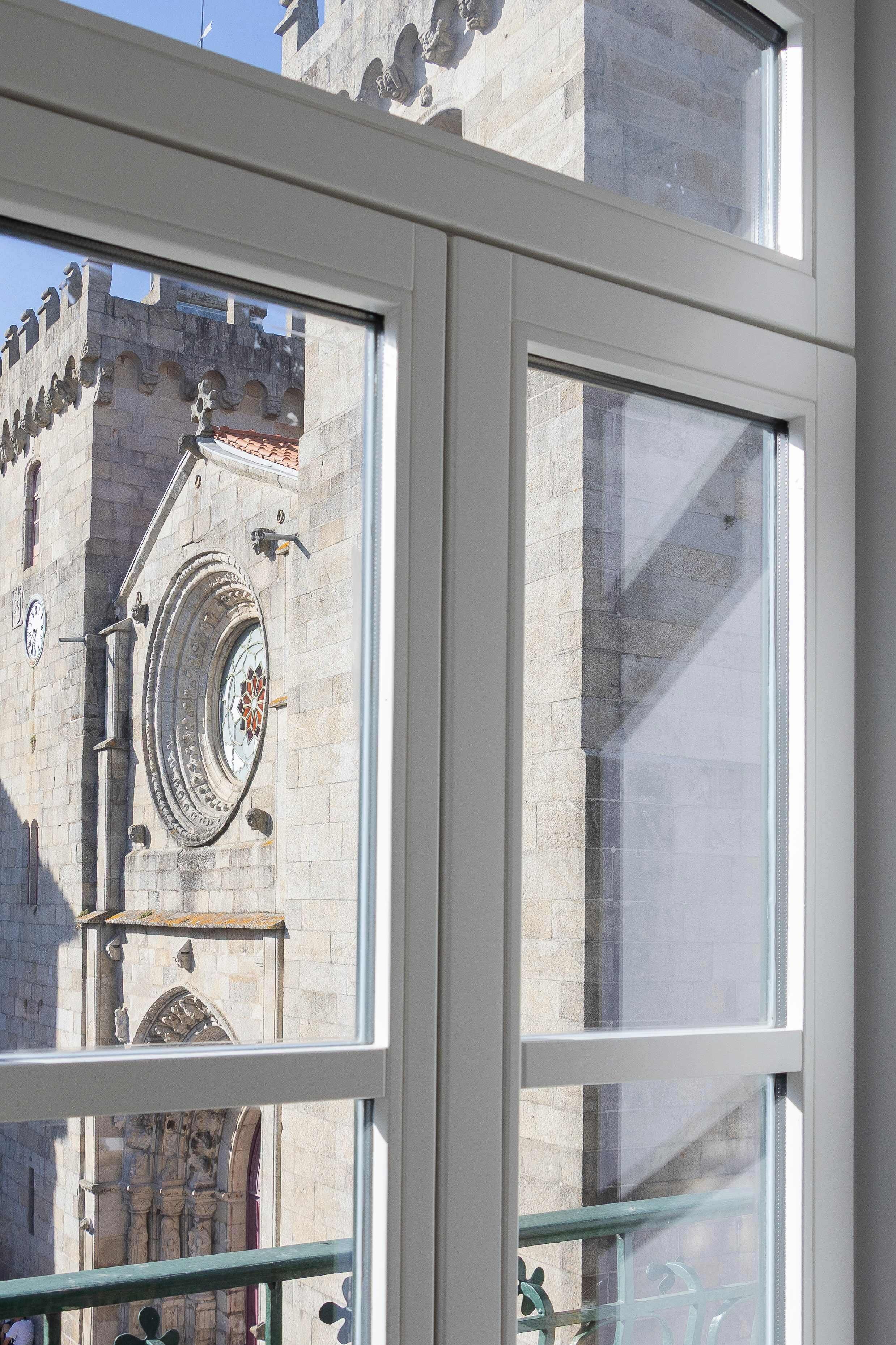 A window with a view of a building's exterior, including a clock and decorative elements.