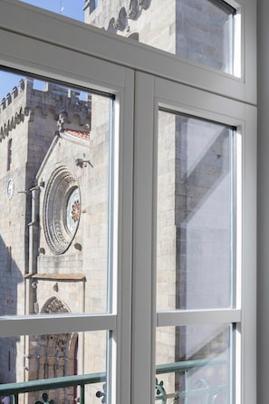 Una finestra con vista sull'esterno di un edificio, che include un orologio e elementi decorativi.