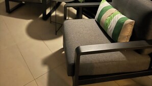 Un coin salon avec deux chaises et une petite table, une plante en pot et un mur avec des volets noirs.